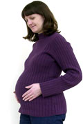 7-month pregnant woman with her hands on her abdomen, smiling