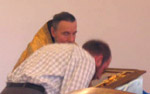 Man with head bowed sitting with a priest