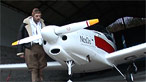 Maggot in a pilot's helmet standing next to a light aircraft